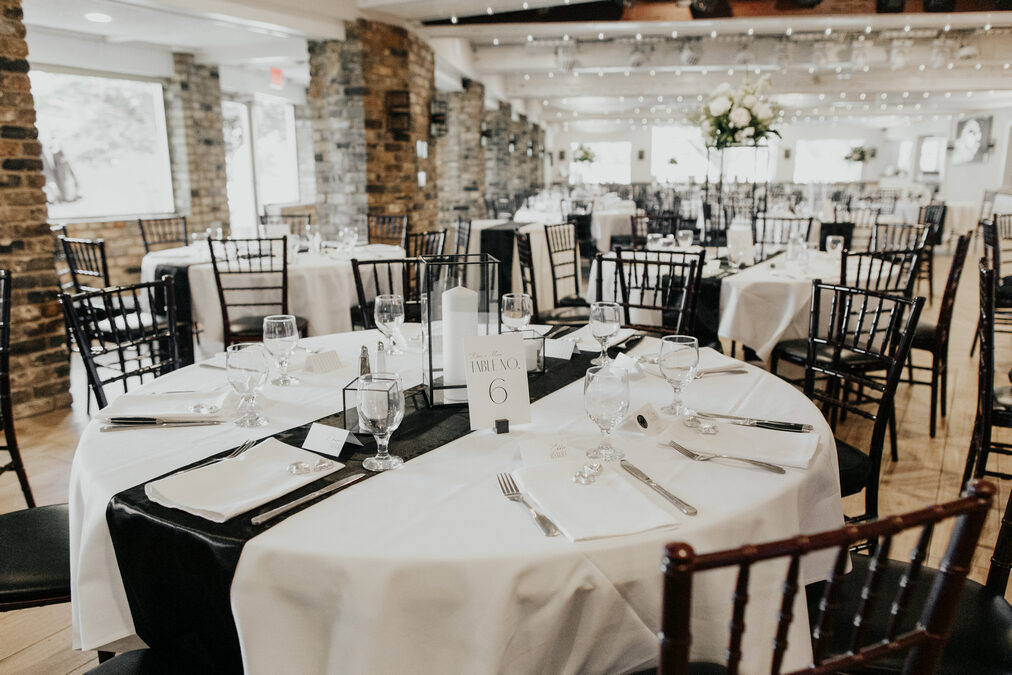 Reception table set with linens and centerpieces beside the lake-view windows in the Kingsley Ballroom at the Chart House, Lakeville MN