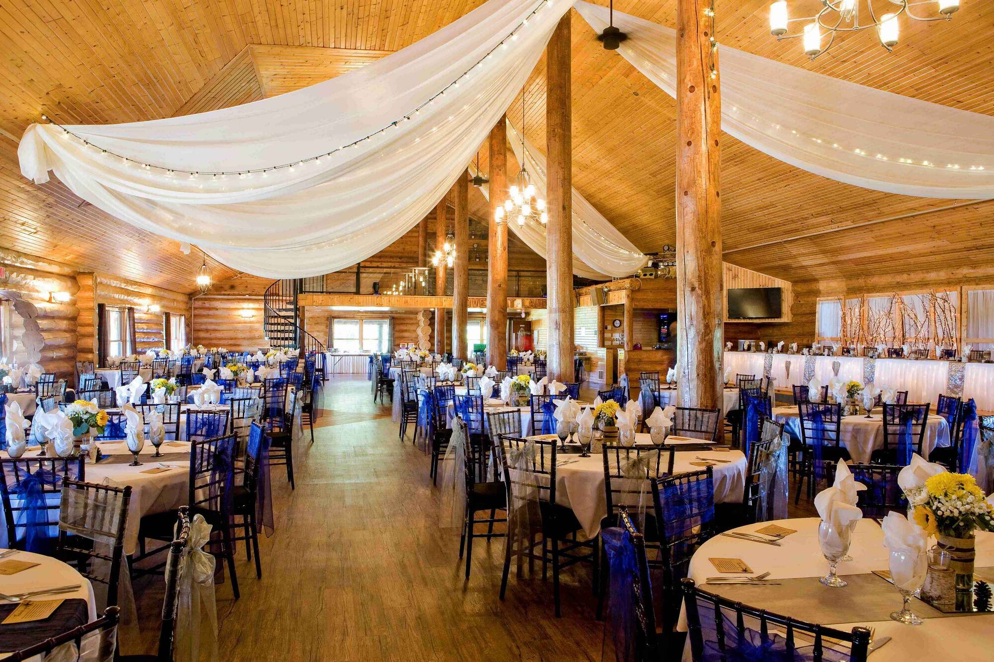 Glenhaven Events ballroom set for a reception with draped ceiling, warm uplighting, and round tables in Farmington MN